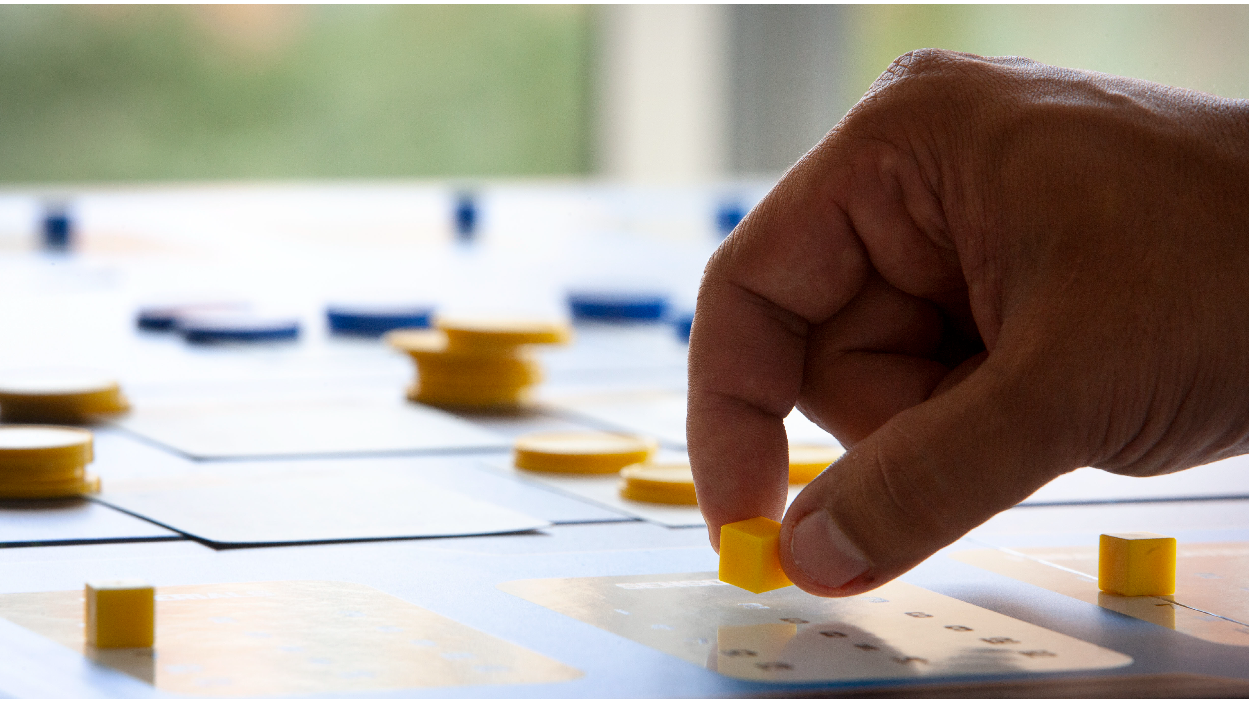 Man's hand moving a yellow cube on a wargaming board