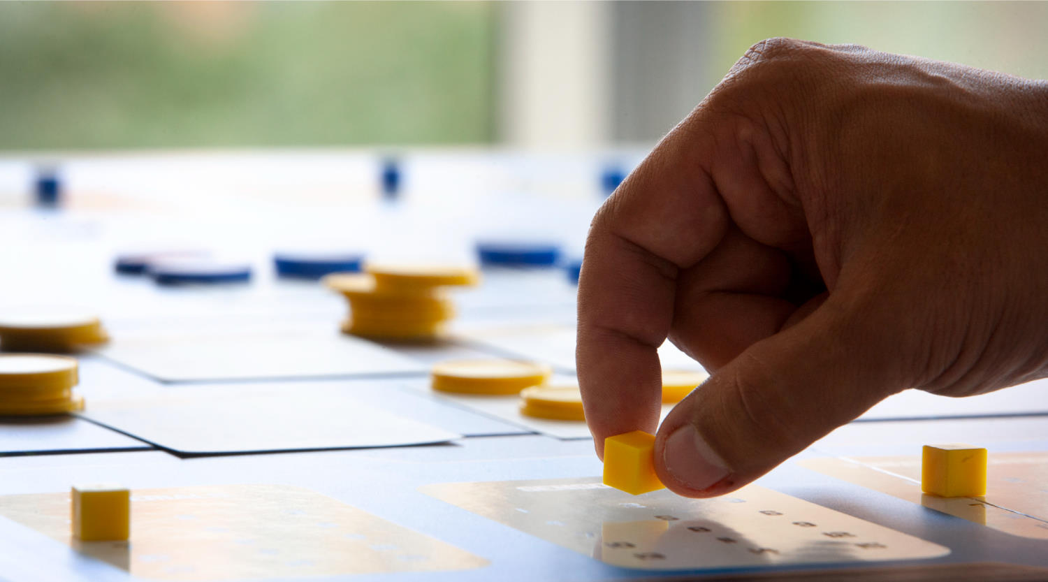 Man's hand moving a yellow cube on a wargaming board