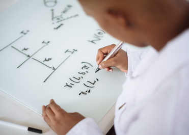 Man writing equations on a whiteboard