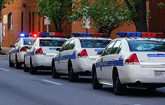 Four police cruisers driving away on a city street