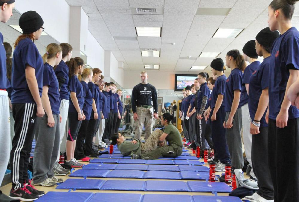 Female Marines enrolled in the Delayed Entry Program demonstrate how to properly perform crunches for an Initial Strength Test  