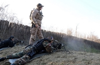 BELGRADE, Serbia-A U.S. Navy SEAL assigned to Naval Special Warfare Unit 2 observes the target as a member of the Serbian Special Anti-terrorist Unit shoots in the prone position on the M249 Squad Automatic Weapon during a Special Operations Command Europe Joint Combined Exchange Training Nov. 28.