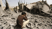 A Yemeni man with his head in his hands in front of rubble