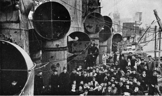 A 1920s photo of a naval vessel with many people posing for picture