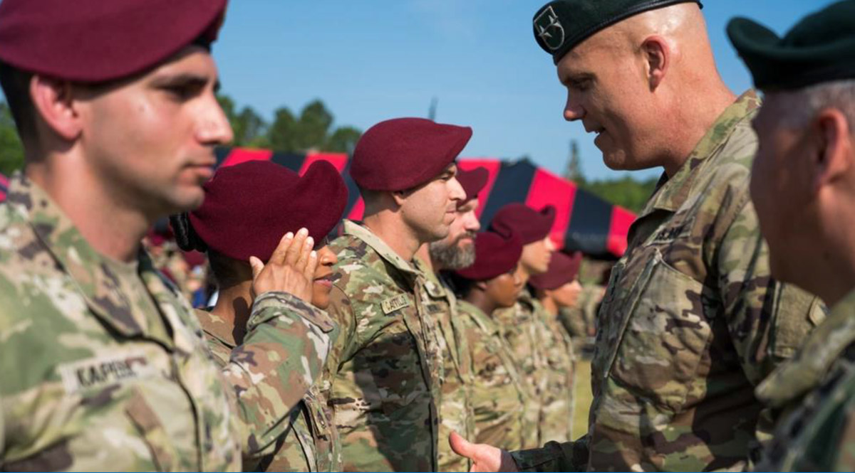 Major General John Deedrick, 1st Special Forces Command (Airborne) commanding general, offers a coin to a newly promoted psychological operations noncommissioned officer during a promotion ceremony larger than any other in Army special operations history.