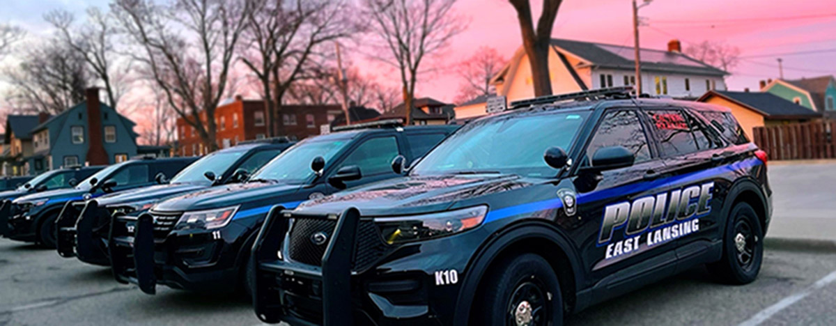 East Lansing police cruisers parked so the police department name is visable on the side door