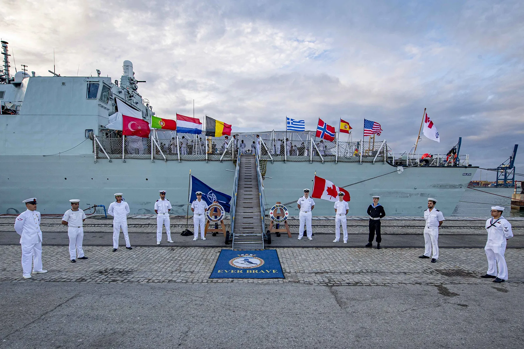sailor and flags of NATO countries in front of Royal Canadian Navy frigate
