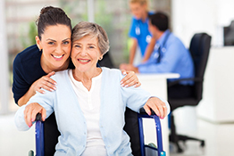 Woman with her hands on the shoulders of a woman in a wheelchair