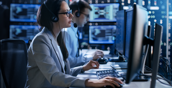 A woman sitting at a computer it what seems to be a control center